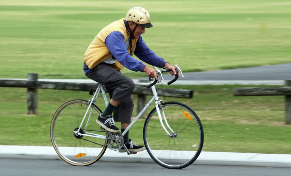 Um senhor de idade pedala animado sua bicicleta