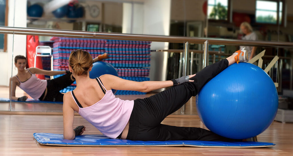 mulher praticando pilates com bola em uma acedemia
